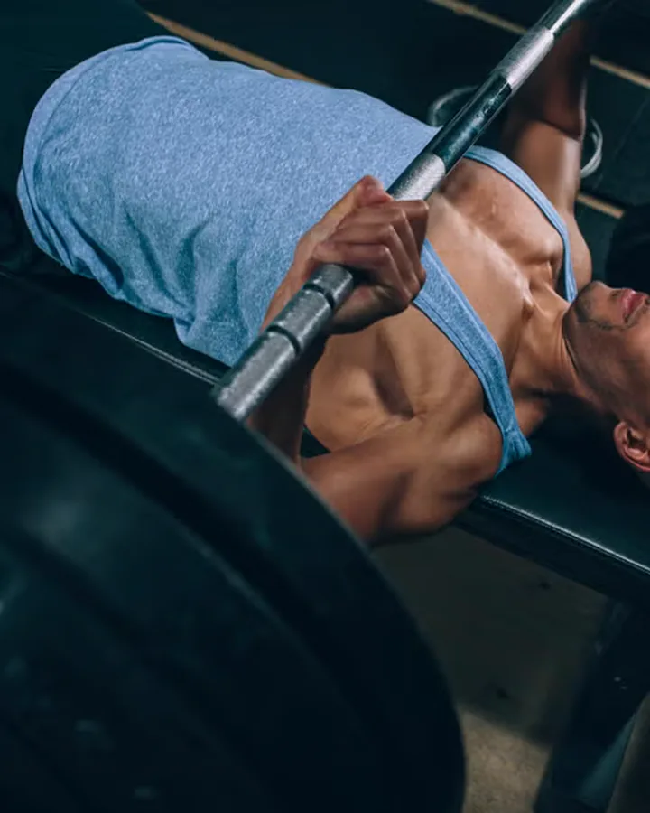 An athlete under a loaded barbell in a concrete gym.